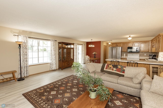 2383 58th Ave S Unit A, Fargo, ND 58104 - living area with light wood finished floors, a chandelier, and a textured ceiling