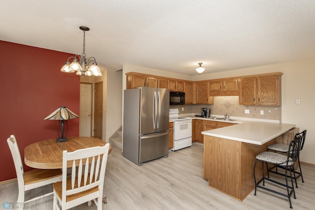 2383 58th Ave S Unit A, Fargo, ND 58104 - kitchen with freestanding refrigerator, white range with electric cooktop, black microwave, a peninsula, and light wood-style floors