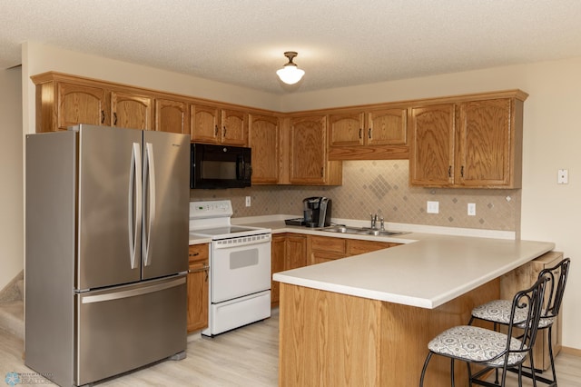 2383 58th Ave S Unit A, Fargo, ND 58104 - kitchen featuring freestanding refrigerator, black microwave, electric range, a peninsula, and light wood-style flooring
