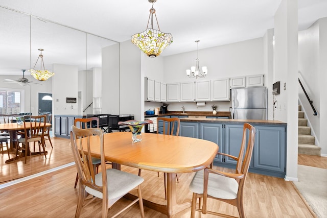 2304 Wildwood Trl, Minnetonka, MN 55305 - dining area with stairway, a towering ceiling, ceiling fan, light wood-style floors, and a chandelier
