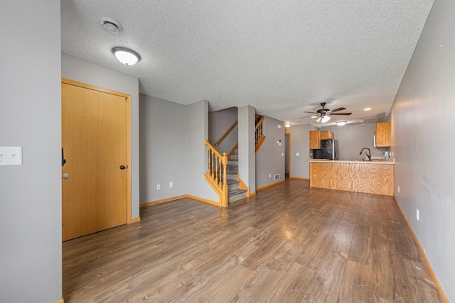 345 Roosevelt St S Unit C, Cambridge, MN 55008 - unfurnished living room featuring a textured ceiling, wood finished floors, a sink, a ceiling fan, and stairway