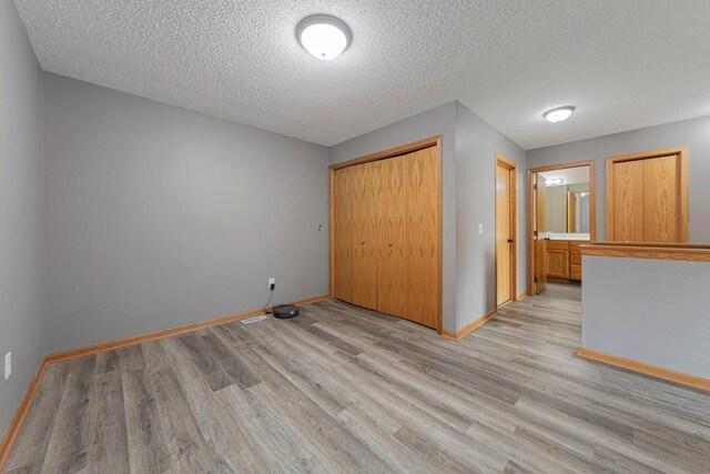 345 Roosevelt St S Unit C, Cambridge, MN 55008 - unfurnished bedroom with light wood finished floors, baseboards, a closet, and a textured ceiling