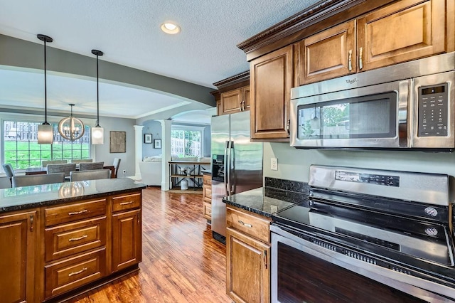 5112 Willow Ln, Minnetonka, MN 55345 - kitchen with appliances with stainless steel finishes, arched walkways, wood finished floors, crown molding, and pendant lighting