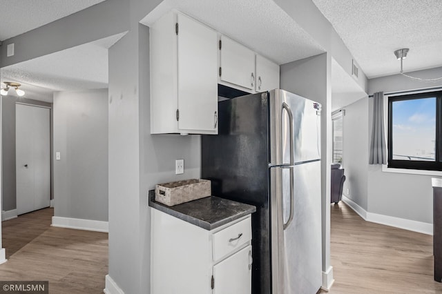 26 10th St W Unit 1409, Saint Paul, MN 55102 - kitchen with freestanding refrigerator, a textured ceiling, light wood-style flooring, white cabinets, and dark countertops