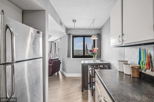 26 10th St W Unit 1409, Saint Paul, MN 55102 - kitchen with freestanding refrigerator, dark countertops, light wood-style flooring, a textured ceiling, and white cabinets