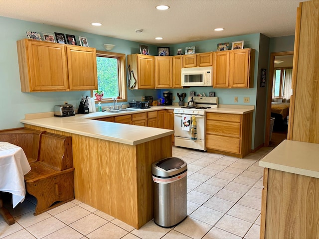 24080 Washington Dr, Osage, MN 56570 - kitchen featuring white appliances, a peninsula, a sink, light countertops, and light tile patterned floors