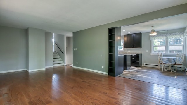 603 15th St SE, Menomonie, WI 54751 - unfurnished living room with wood finished floors, stairway, a baseboard heating unit, and baseboards