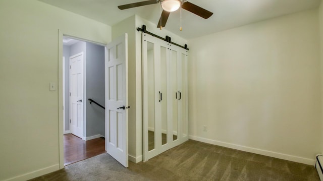 603 15th St SE, Menomonie, WI 54751 - unfurnished bedroom featuring a barn door, carpet, baseboards, baseboard heating, and a ceiling fan