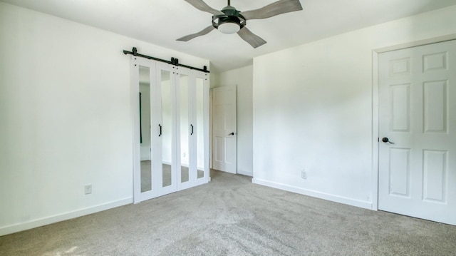 603 15th St SE, Menomonie, WI 54751 - unfurnished bedroom with a barn door, carpet, baseboards, and a ceiling fan