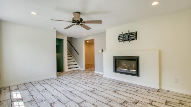 603 15th St SE, Menomonie, WI 54751 - unfurnished living room featuring stairway, ceiling fan, wood finished floors, a glass covered fireplace, and recessed lighting