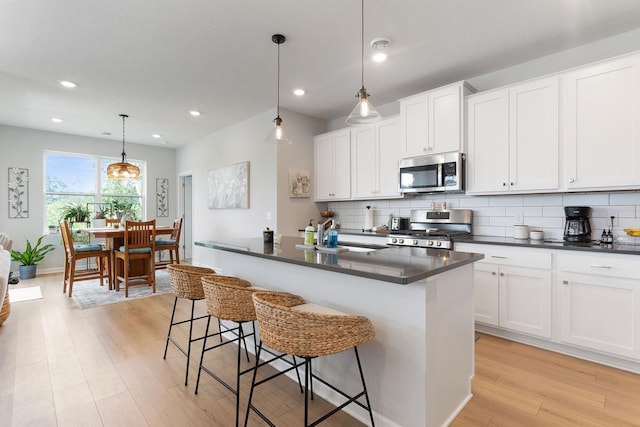 15730 Goodview Trl N, Hugo, MN 55038 - kitchen featuring appliances with stainless steel finishes, dark countertops, light wood-style floors, decorative backsplash, and recessed lighting