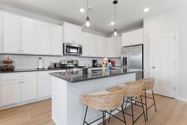 15730 Goodview Trl N, Hugo, MN 55038 - kitchen featuring appliances with stainless steel finishes, dark countertops, light wood finished floors, backsplash, and recessed lighting