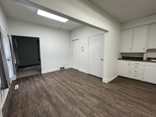 501 River St, Colfax, WI 54730 - kitchen with dark wood-type flooring, white cabinets, dark countertops, baseboards, and a drop ceiling