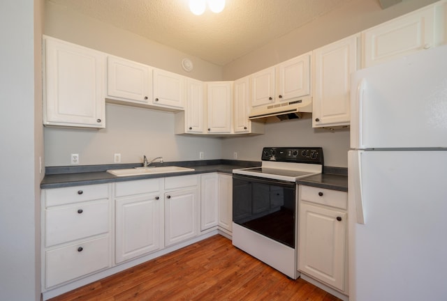 11 1st St, Nashwauk, MN 55769 - kitchen featuring freestanding refrigerator, range with electric cooktop, under cabinet range hood, dark countertops, and a textured ceiling