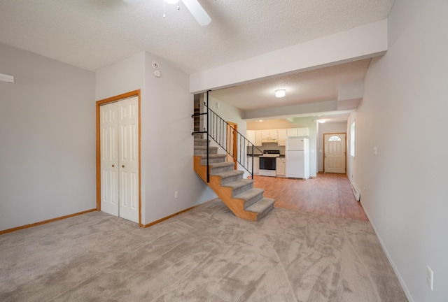 11 1st St, Nashwauk, MN 55769 - unfurnished living room featuring light colored carpet, stairway, ceiling fan, and a textured ceiling