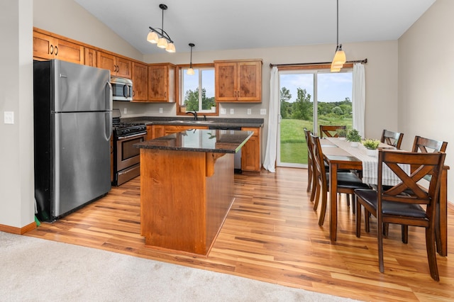 3322 Orchard Ave NE, Sauk Rapids, MN 56379 - kitchen featuring appliances with stainless steel finishes, light wood finished floors, a kitchen island, vaulted ceiling, and brown cabinets