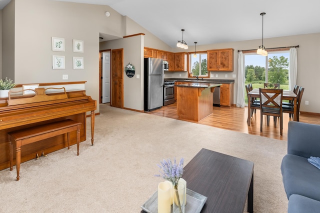 3322 Orchard Ave NE, Sauk Rapids, MN 56379 - kitchen featuring appliances with stainless steel finishes, light carpet, vaulted ceiling, open floor plan, and dark countertops