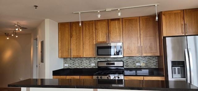 929 Portland Ave Unit 2205, Minneapolis, MN 55404 - kitchen with stainless steel appliances, dark countertops, rail lighting, backsplash, and brown cabinetry