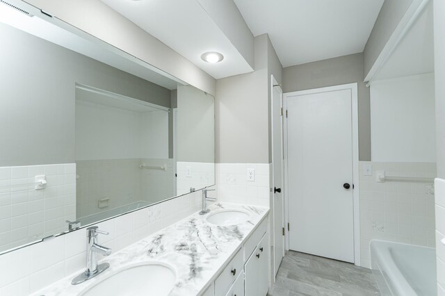 912 11 1/2 St SW, Rochester, MN 55902 - bathroom featuring tile walls, double vanity, a tub to relax in, a wainscoted wall, and marble finish flooring