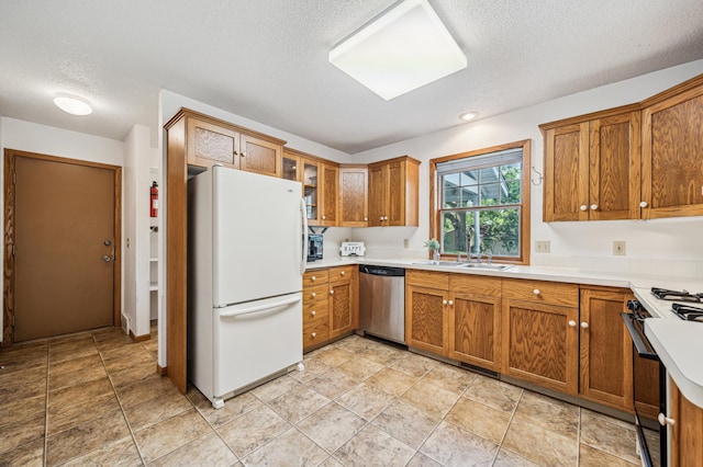741 3rd St NE, Faribault, MN 55021 - kitchen featuring freestanding refrigerator, stainless steel dishwasher, range with gas stovetop, brown cabinets, and a textured ceiling