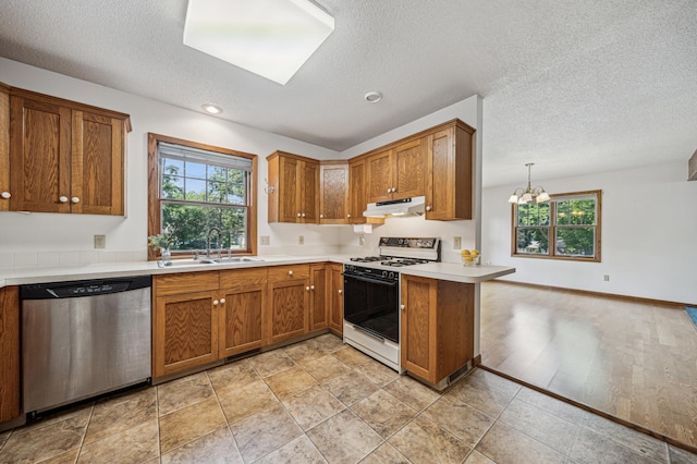 741 3rd St NE, Faribault, MN 55021 - kitchen with gas range, stainless steel dishwasher, under cabinet range hood, a textured ceiling, and brown cabinets