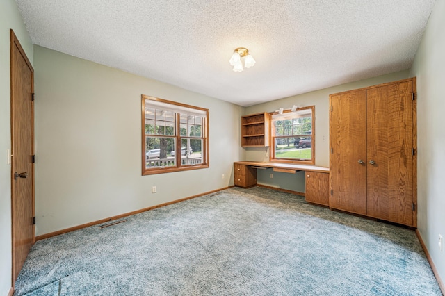 741 3rd St NE, Faribault, MN 55021 - unfurnished bedroom featuring built in desk, carpet flooring, a textured ceiling, and a closet