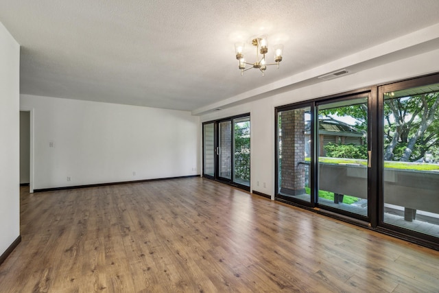 6417 Colony Way Unit 2A, Edina, MN 55435 - empty room with a chandelier, wood finished floors, baseboards, and a textured ceiling