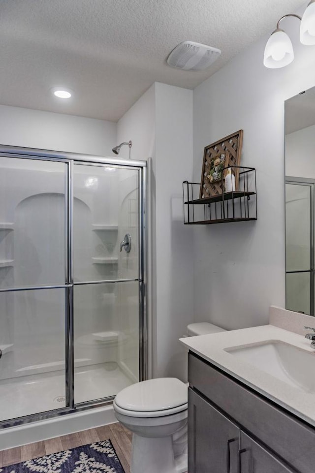 882 Redmond Dr, Carver, MN 55315 - full bathroom featuring a textured ceiling, toilet, vanity, a shower stall, and wood finished floors