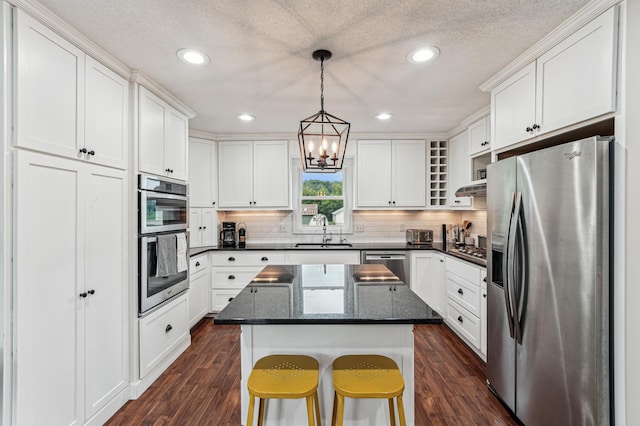 18160 Echo Ave, Faribault, MN 55021 - kitchen with stainless steel appliances, dark wood-style floors, a chandelier, white cabinets, and decorative backsplash