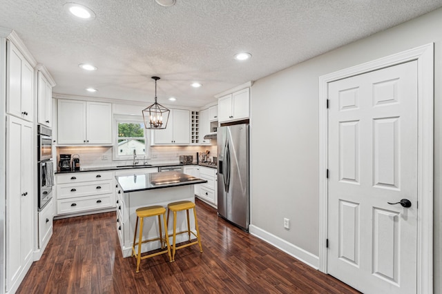 18160 Echo Ave, Faribault, MN 55021 - kitchen with appliances with stainless steel finishes, dark countertops, decorative backsplash, a kitchen island, and dark wood-type flooring