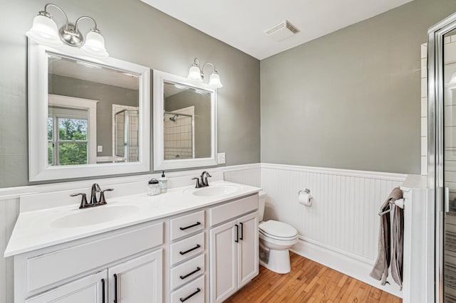 18160 Echo Ave, Faribault, MN 55021 - bathroom with wood finished floors, double vanity, a wainscoted wall, and tiled shower