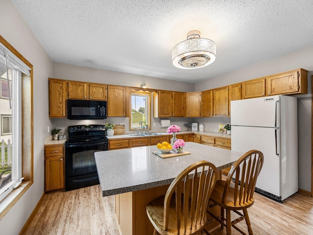 45 Oak Ave S, Maple Lake, MN 55358 - kitchen with black appliances, light wood finished floors, a textured ceiling, a breakfast bar area, and a kitchen island