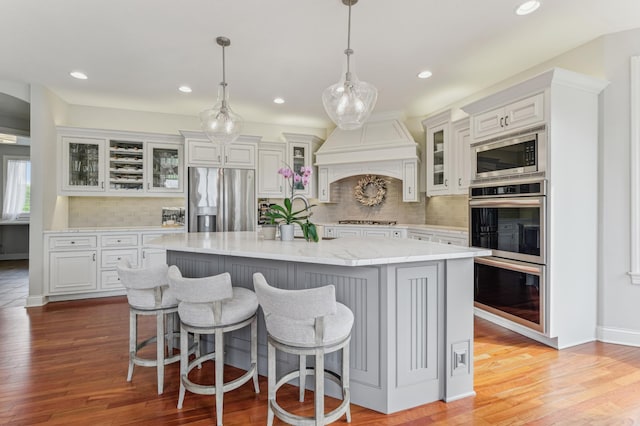 3287 Norcrest Ave N, Baytown Twp, MN 55082 - kitchen with stainless steel appliances, decorative backsplash, an island with sink, light wood finished floors, and recessed lighting
