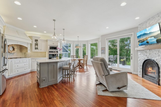 3287 Norcrest Ave N, Baytown Twp, MN 55082 - kitchen featuring appliances with stainless steel finishes, open floor plan, a stone fireplace, light countertops, and wood-type flooring