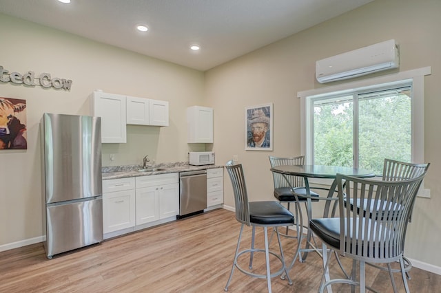 1994 80th St, Somerset, WI 54025 - kitchen featuring appliances with stainless steel finishes, a wall mounted AC, baseboards, white cabinetry, and recessed lighting