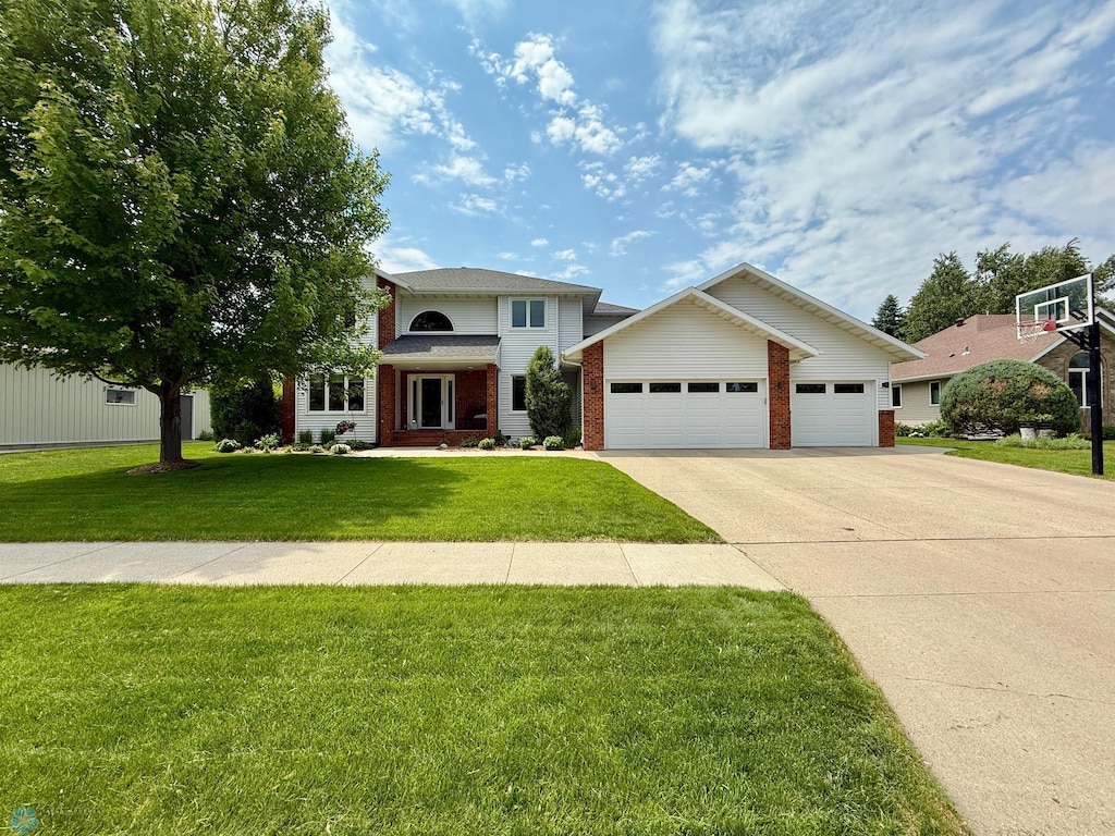 4127 Rivershore Dr, Moorhead, MN 56560 - traditional-style house featuring concrete driveway, an attached garage, brick siding, and a front lawn