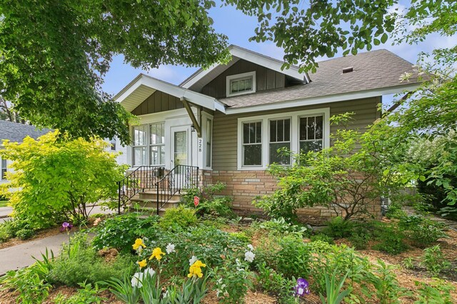 228 Sidney St W, Saint Paul, MN 55107 - view of front of home featuring board and batten siding, a shingled roof, and stone siding