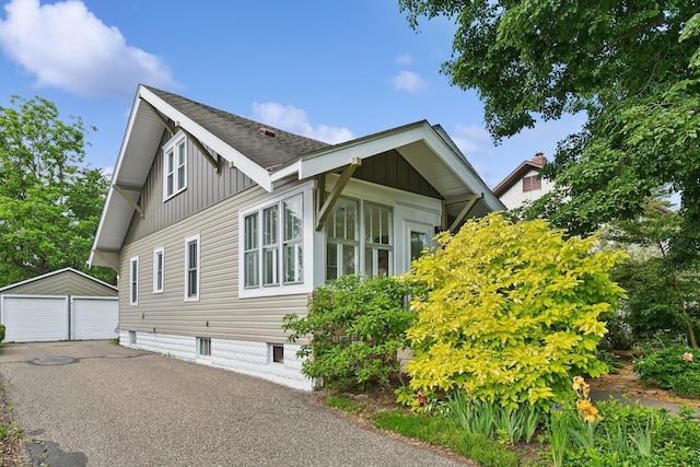 228 Sidney St W, Saint Paul, MN 55107 - view of property exterior with a garage, an outdoor structure, a shingled roof, and board and batten siding
