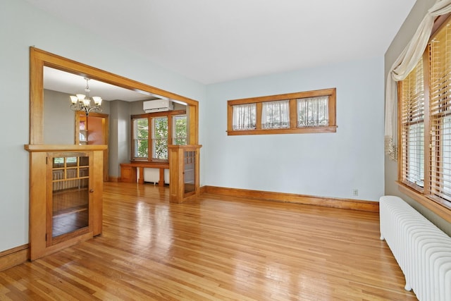 228 Sidney St W, Saint Paul, MN 55107 - empty room featuring radiator heating unit, an AC wall unit, light wood-style floors, and a chandelier