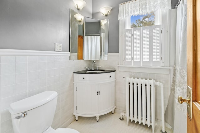 228 Sidney St W, Saint Paul, MN 55107 - full bath featuring radiator heating unit, tile walls, vanity, tile patterned flooring, and wainscoting