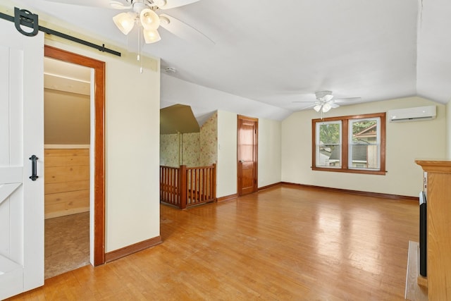 228 Sidney St W, Saint Paul, MN 55107 - unfurnished living room featuring a ceiling fan, a wall mounted air conditioner, light wood-type flooring, a barn door, and vaulted ceiling
