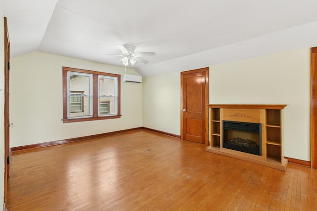 228 Sidney St W, Saint Paul, MN 55107 - unfurnished living room with a wall mounted air conditioner, light wood-style floors, vaulted ceiling, ceiling fan, and a glass covered fireplace