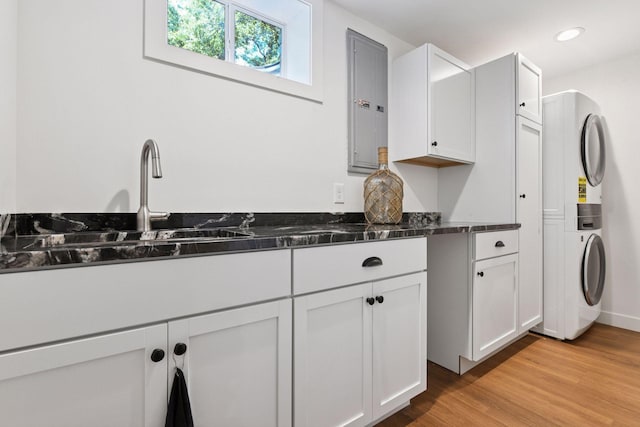 3930 Cottage Ln, Minnetonka, MN 55305 - kitchen with stacked washer and clothes dryer, white cabinets, light wood-style flooring, recessed lighting, and electric panel