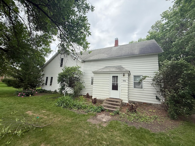 306 1st St, Belview, MN 56214 - back of property featuring entry steps, a chimney, a yard, and a shingled roof