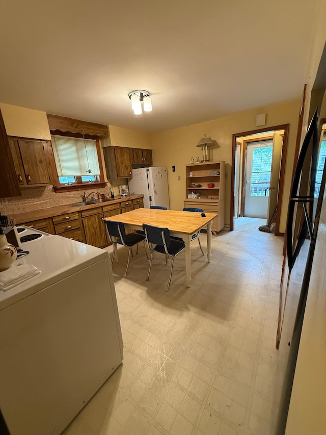 306 1st St, Belview, MN 56214 - kitchen with white fridge with ice dispenser, light flooring, washer / clothes dryer, and brown cabinets