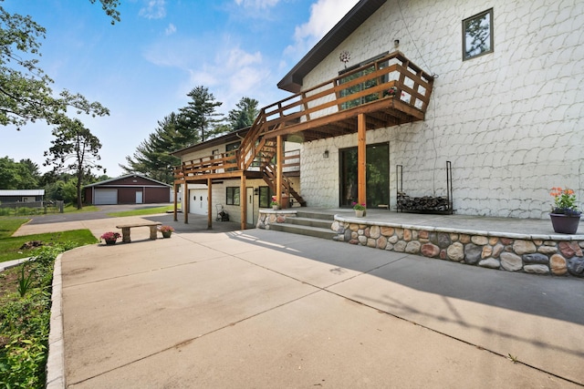 17855 Round Lake Blvd NW, Andover, MN 55304 - rear view of house featuring concrete driveway, a wooden deck, stairs, a detached garage, and an outbuilding