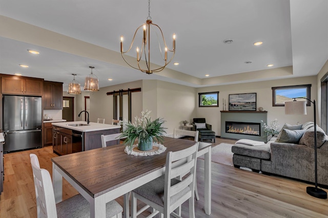 5815 Rivers Edge Dr, Saint Cloud, MN 56303 - dining room featuring a barn door, light wood-style floors, a raised ceiling, recessed lighting, and a glass covered fireplace