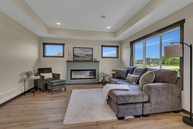 5815 Rivers Edge Dr, Saint Cloud, MN 56303 - living room with a glass covered fireplace, a raised ceiling, light wood-style flooring, baseboards, and recessed lighting