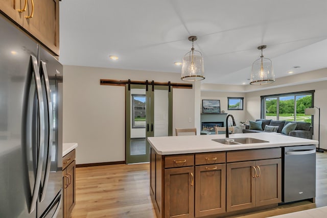 5815 Rivers Edge Dr, Saint Cloud, MN 56303 - kitchen featuring stainless steel appliances, a barn door, a sink, light wood-type flooring, and light countertops