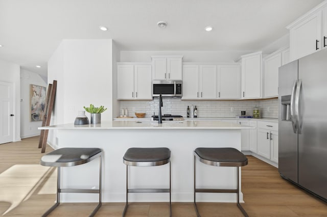 3908 Helmo Ave N, Oakdale, MN 55128 - kitchen with stainless steel appliances, a kitchen breakfast bar, backsplash, recessed lighting, and white cabinets